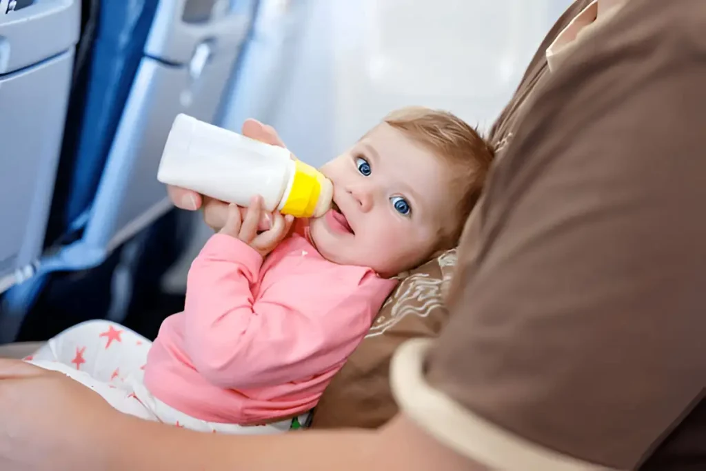 Air travel with baby, Baby girl drinking formula milk from bottle.