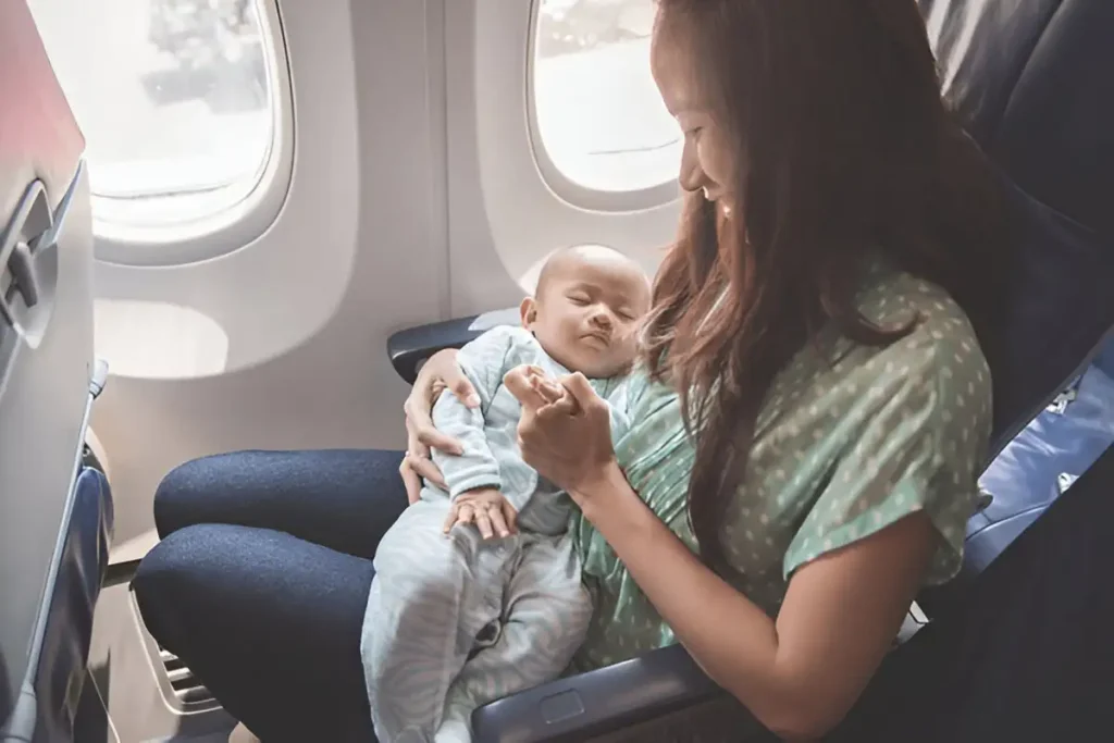 best way to travel with a baby on a plane. Happy mother and baby sitting together in airplane.
